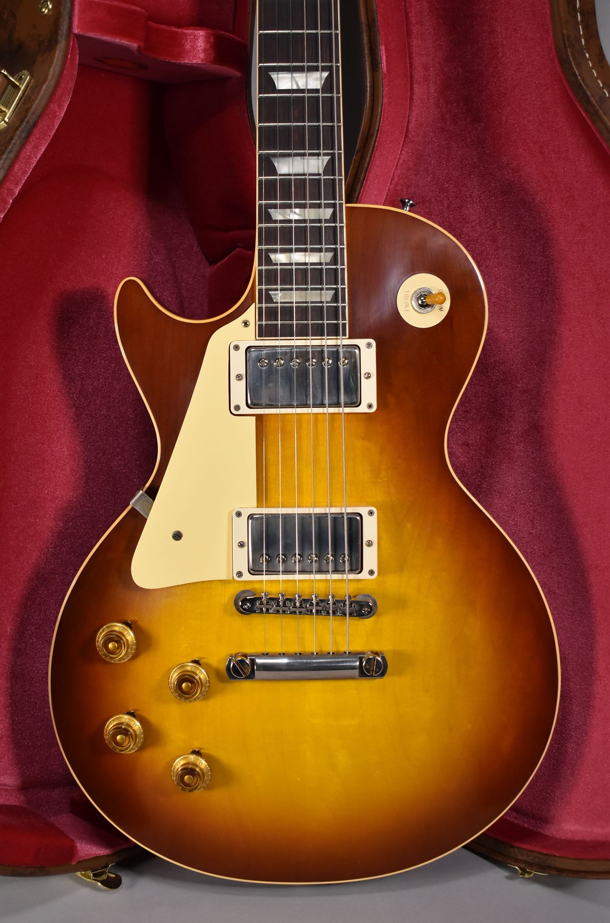 The Les Paul's Iced Tea Burst body, with cream binding and pickguard, is framed from the neck joint to the bottom strap button.