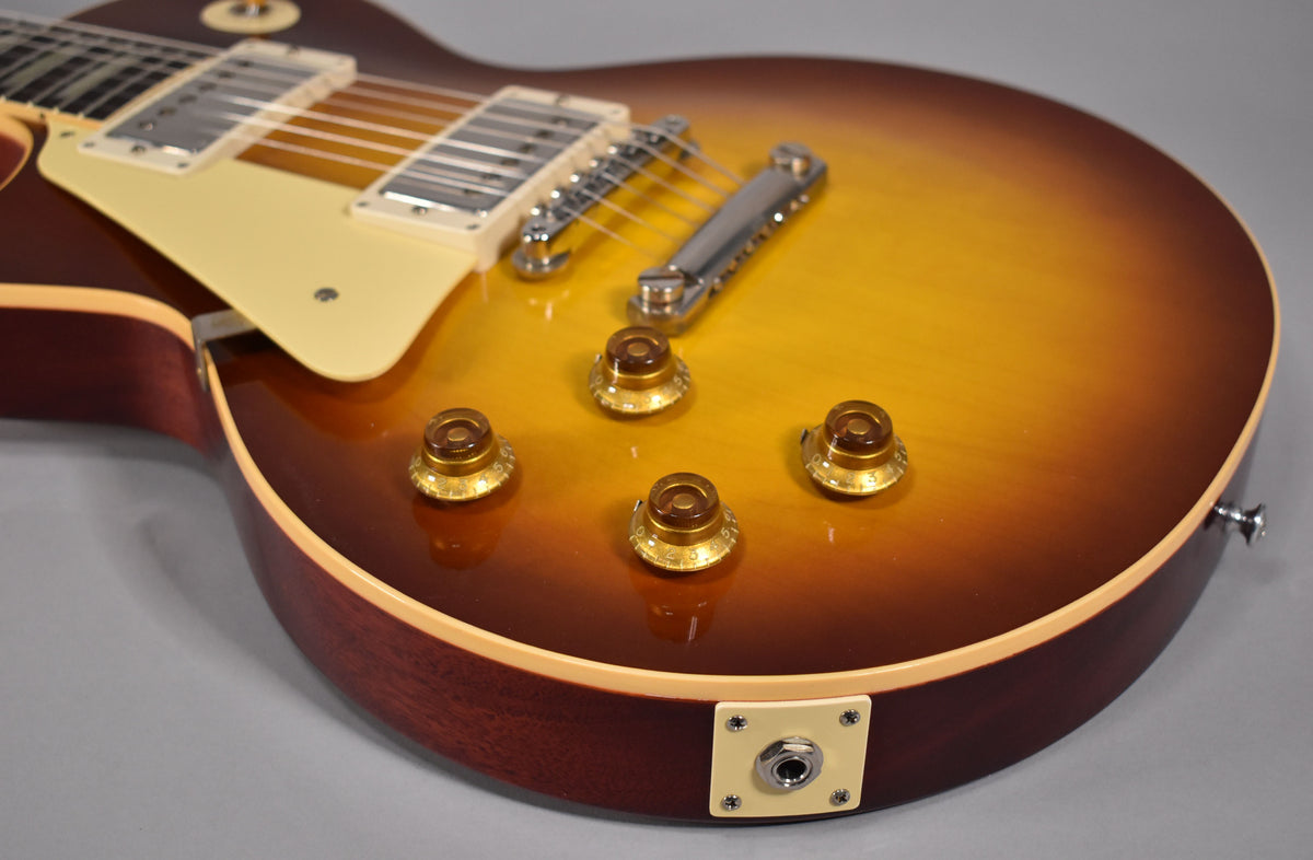 Close-up of the guitar's lower body, showing the iced tea burst finish, four amber control knobs, and the output jack.