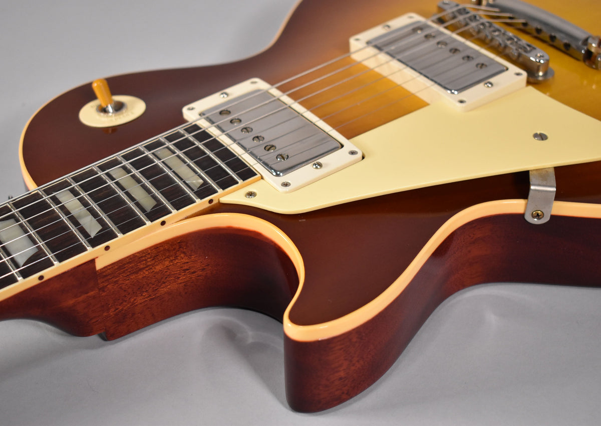 Close-up of the guitar's body, showing the iced tea burst finish, cream binding, pickguard, two humbuckers, and toggle switch.