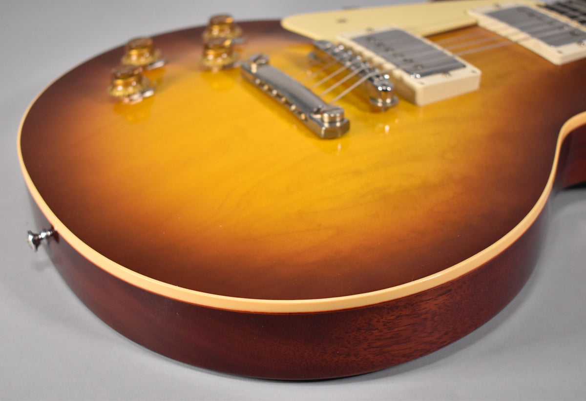 Close-up of the guitar's lower bout, showing the iced tea burst finish, cream binding, and mahogany side with a strap button.