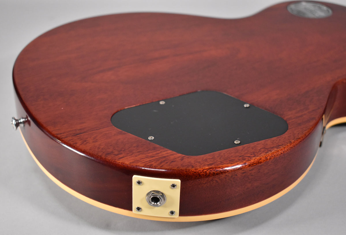 The guitar's back shows a rich iced tea burst finish, a black control cavity cover, and a cream output jack plate.