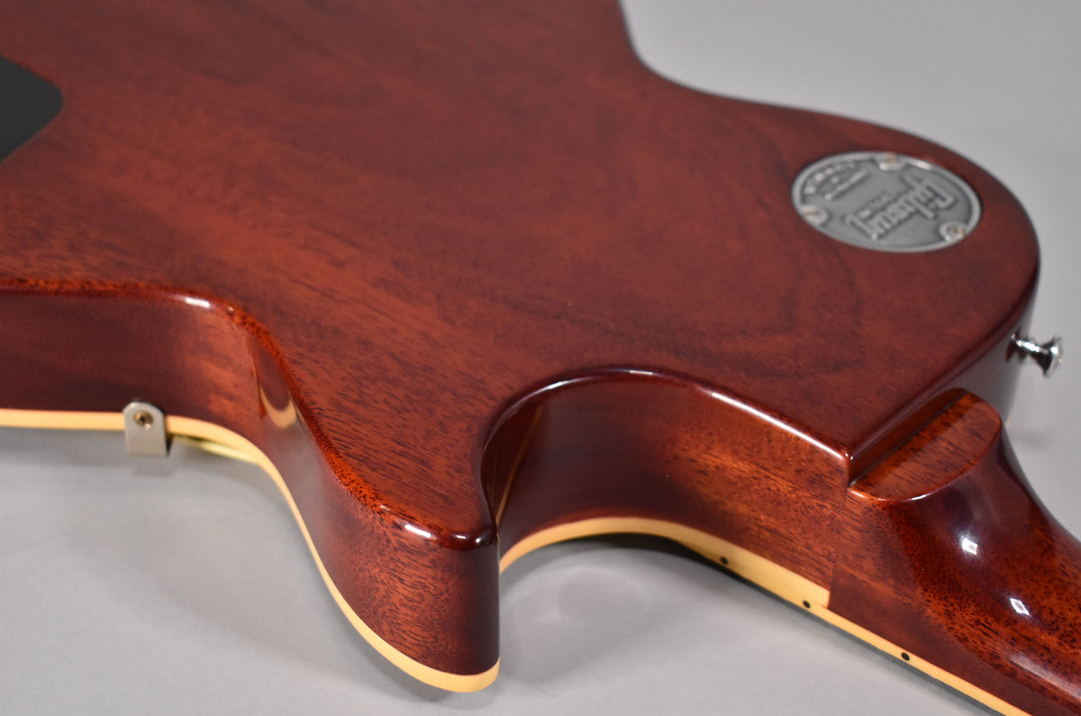 The guitar's dark cherry back and neck heel are visible, with cream binding and a silver medallion on the upper bout.