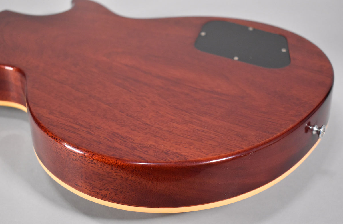 The back of the guitar's body is a rich reddish-brown with visible wood grain, a black control cavity cover, and a chrome strap button.