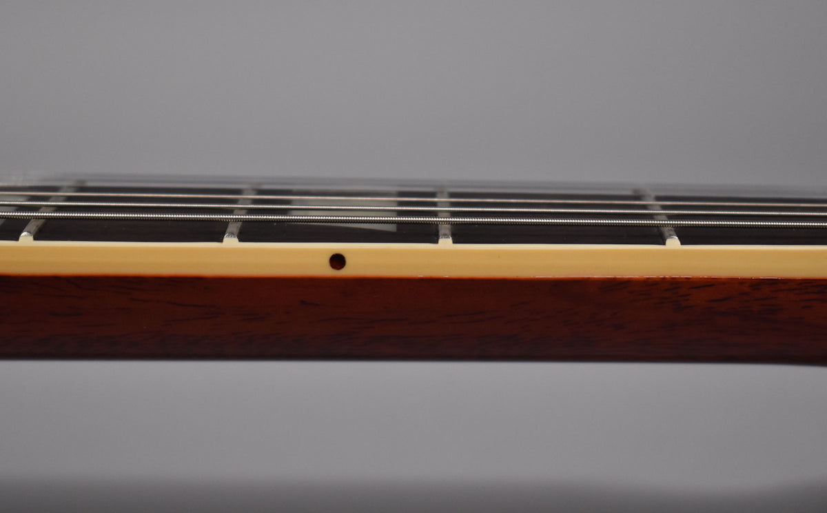 Close-up of the guitar's dark brown neck and cream binding, showing the frets and strings from a side angle.