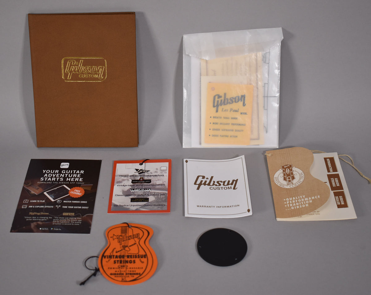A collection of Gibson Custom paperwork and hangtags, including a brown box, white envelope, and various informational cards.