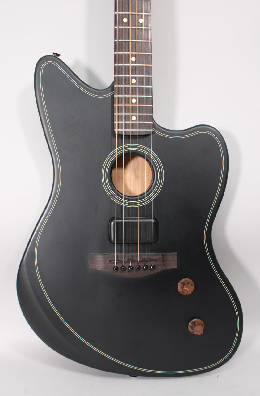Matte black guitar with cream binding, a soundhole, a dark wood bridge, a black pickup, and two wooden control knobs.