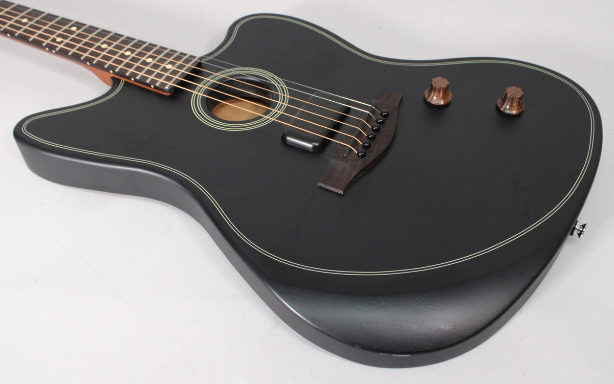 The black matte guitar body, with white binding, is angled from the neck to the lower bout, showing two brown control knobs.