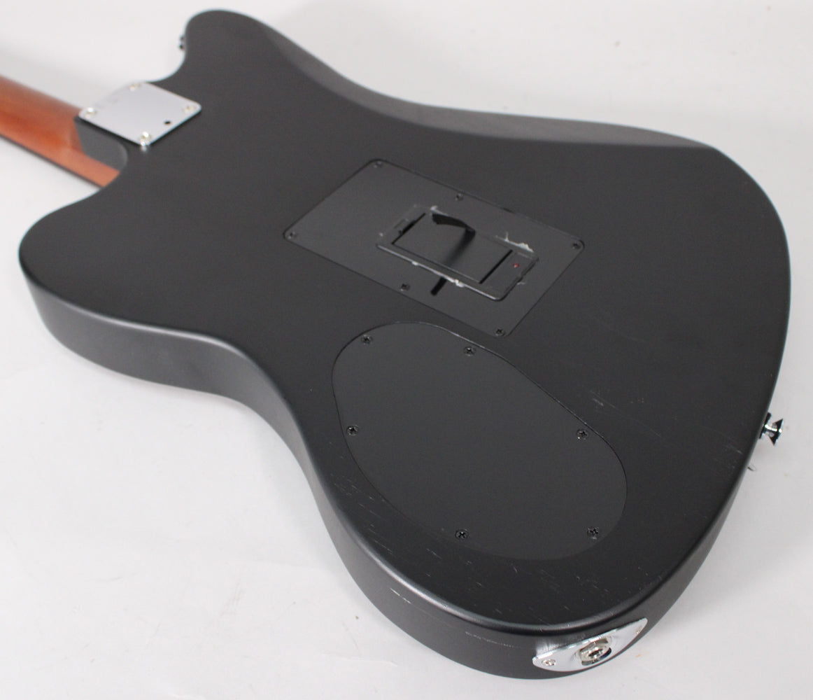 The matte black guitar body's back is angled, revealing a neck plate, two control covers, and a chrome output jack.