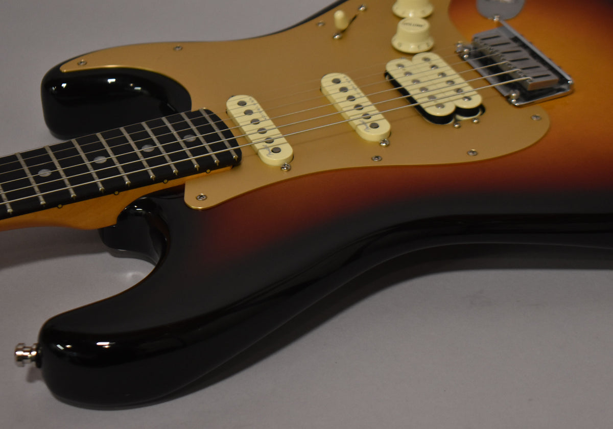 The Ultraburst body, with a gold pickguard, shows a humbucker and two single-coil pickups, plus three cream control knobs.