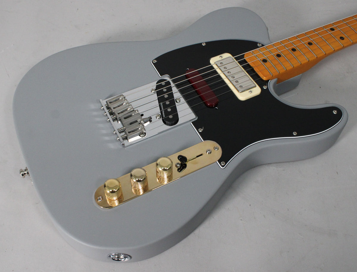 Close-up of a gray Telecaster-style guitar with a black pickguard, gold control plate, and maple neck.