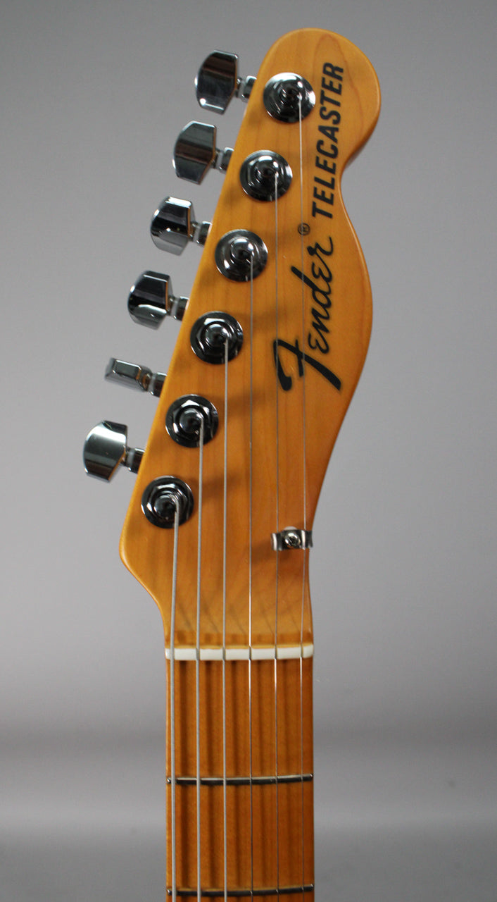 Close-up of the guitar's headstock and upper neck, showing six chrome tuners, a string tree, and a light-colored nut.