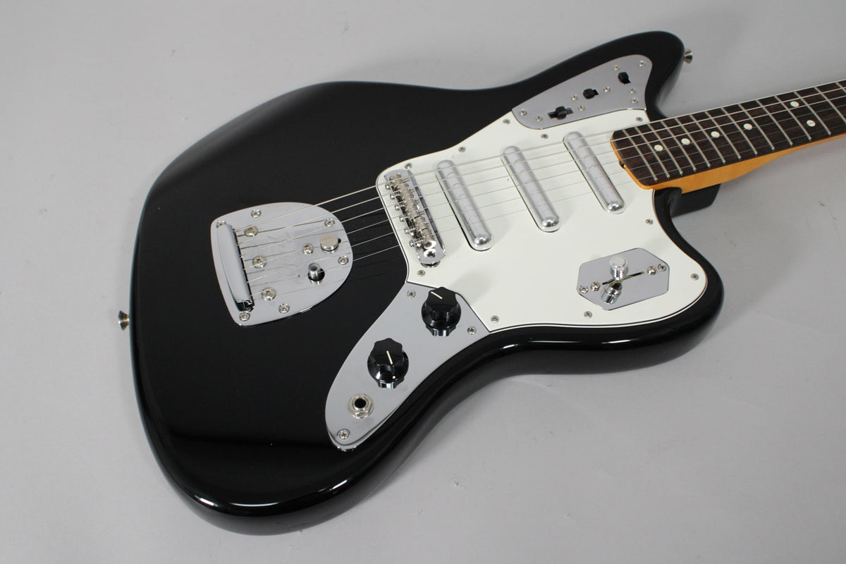 A black electric guitar with a white pickguard, chrome hardware, and a rosewood fretboard, angled from the lower left.