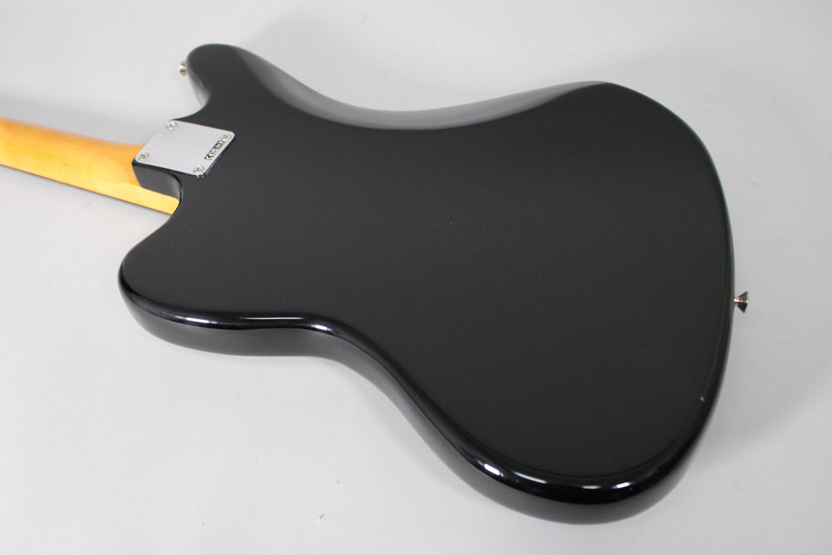 The back of the black Jaguar guitar body is shown from the upper left, with a light maple neck and chrome neck plate.