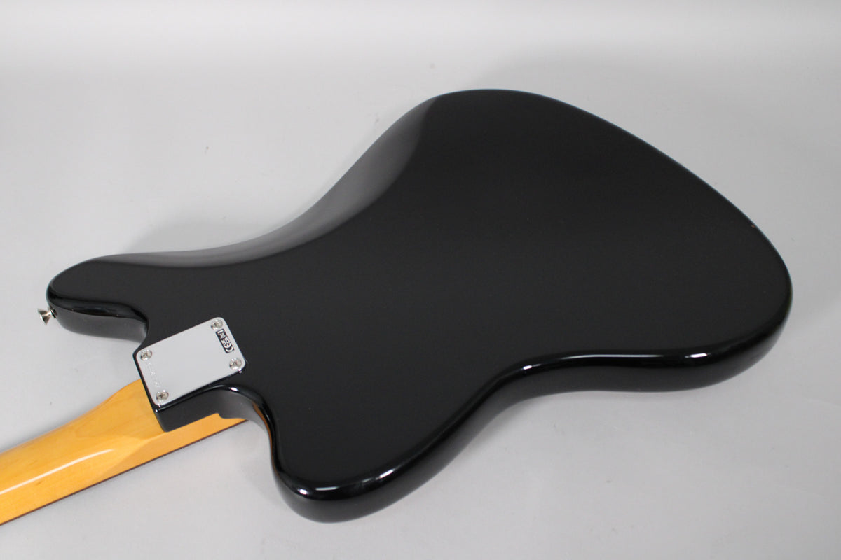 The back of a glossy black electric guitar body with a light-colored maple neck and chrome neck plate.