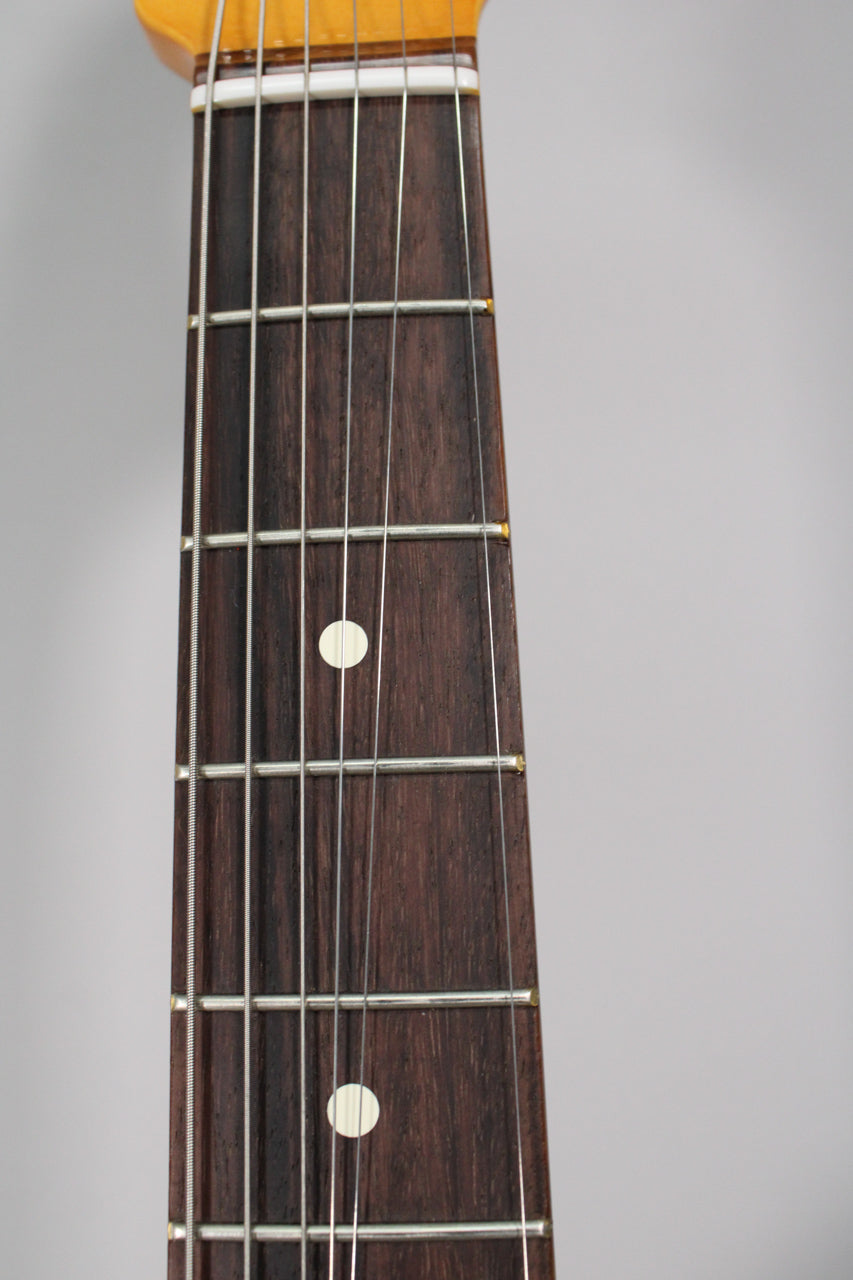 Close-up of the dark rosewood fretboard with white dot inlays, showing frets 1-10 and a bone nut.