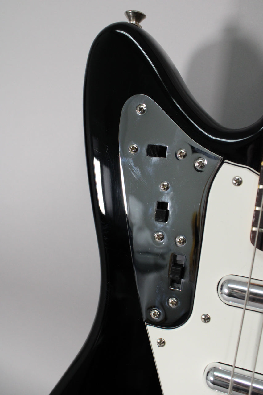 Upper body of a glossy black electric guitar, showing the chrome control plate with three black slider switches and light scratches.