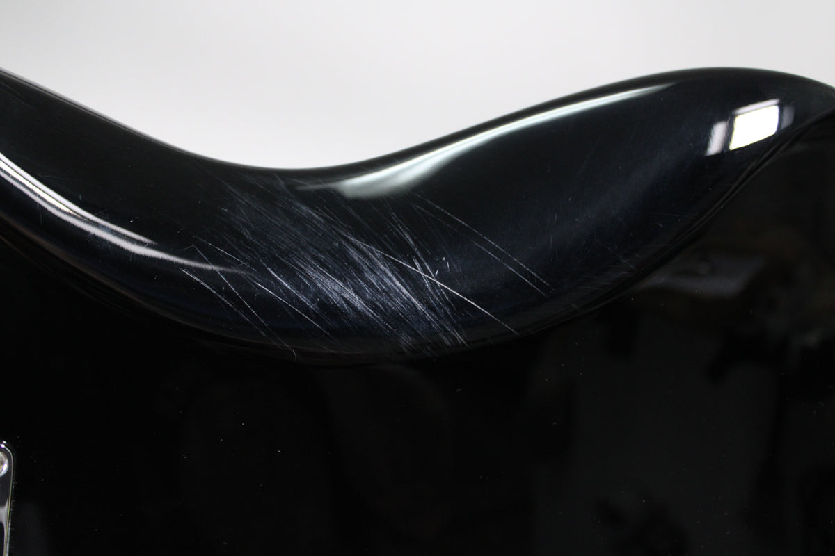 Close-up of the black gloss body, showing a cluster of prominent scratches on the upper bout curve.