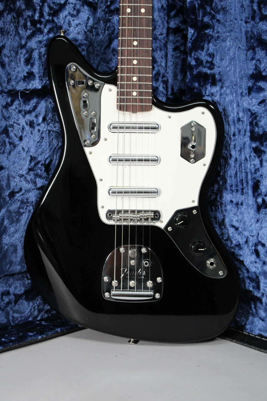 A black electric guitar with a white pickguard and chrome hardware, resting in a blue velvet-lined case.