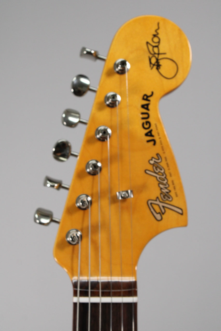 Close-up of the guitar's headstock, angled slightly left, showing six chrome tuners, a string tree, and a light amber finish.