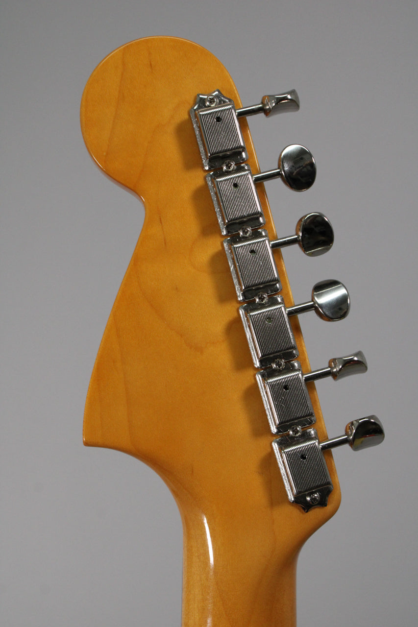 Rear view of the guitar's headstock and top of the neck, showing six chrome vintage-style tuners on a glossy amber finish.