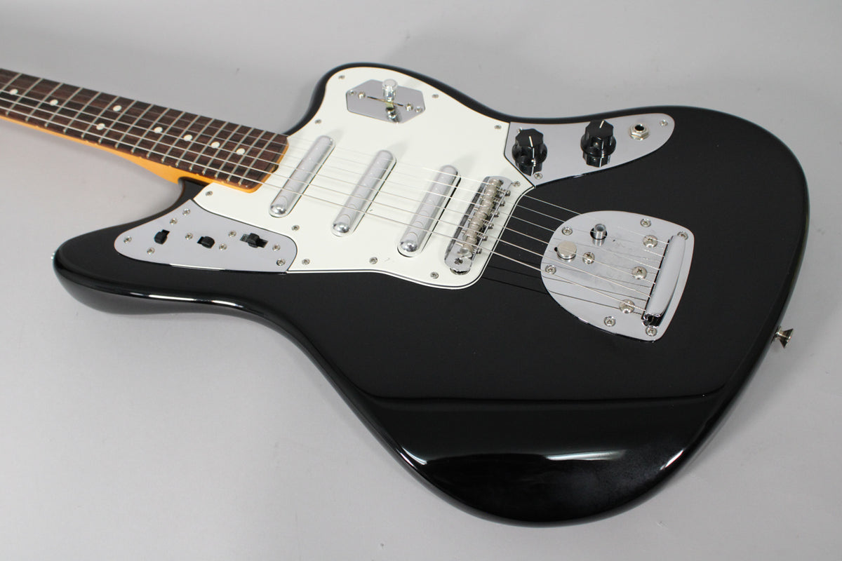A black electric guitar with a white pickguard, chrome hardware, and a rosewood fretboard, angled from the neck to the body.