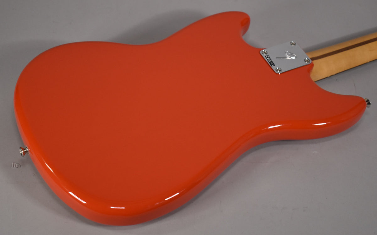 The glossy Rallye Orange bass body is viewed from the back, showing the chrome neck plate and a light wood neck.