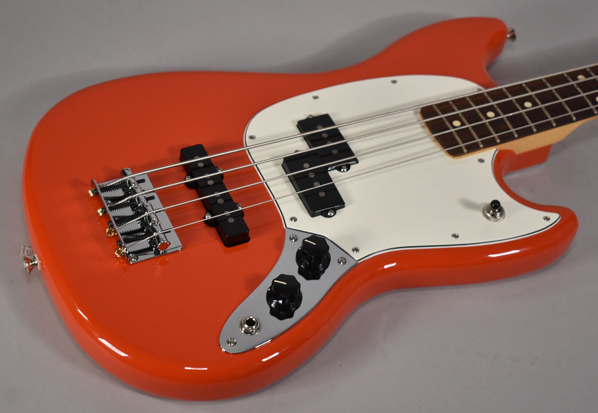 The Rallye Orange bass body, with a white pickguard, chrome bridge, black PJ pickups, and two black control knobs.