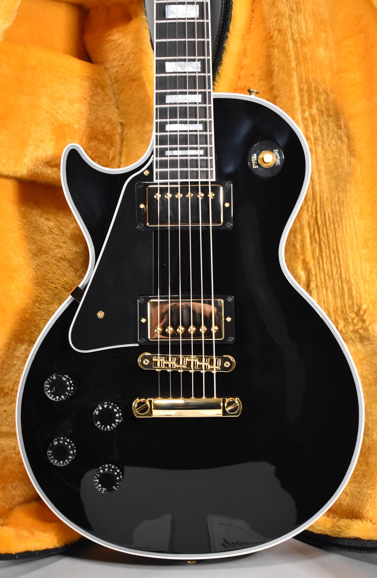 Gloss black electric guitar with gold hardware, two humbuckers, four control knobs, and a three-way toggle switch.