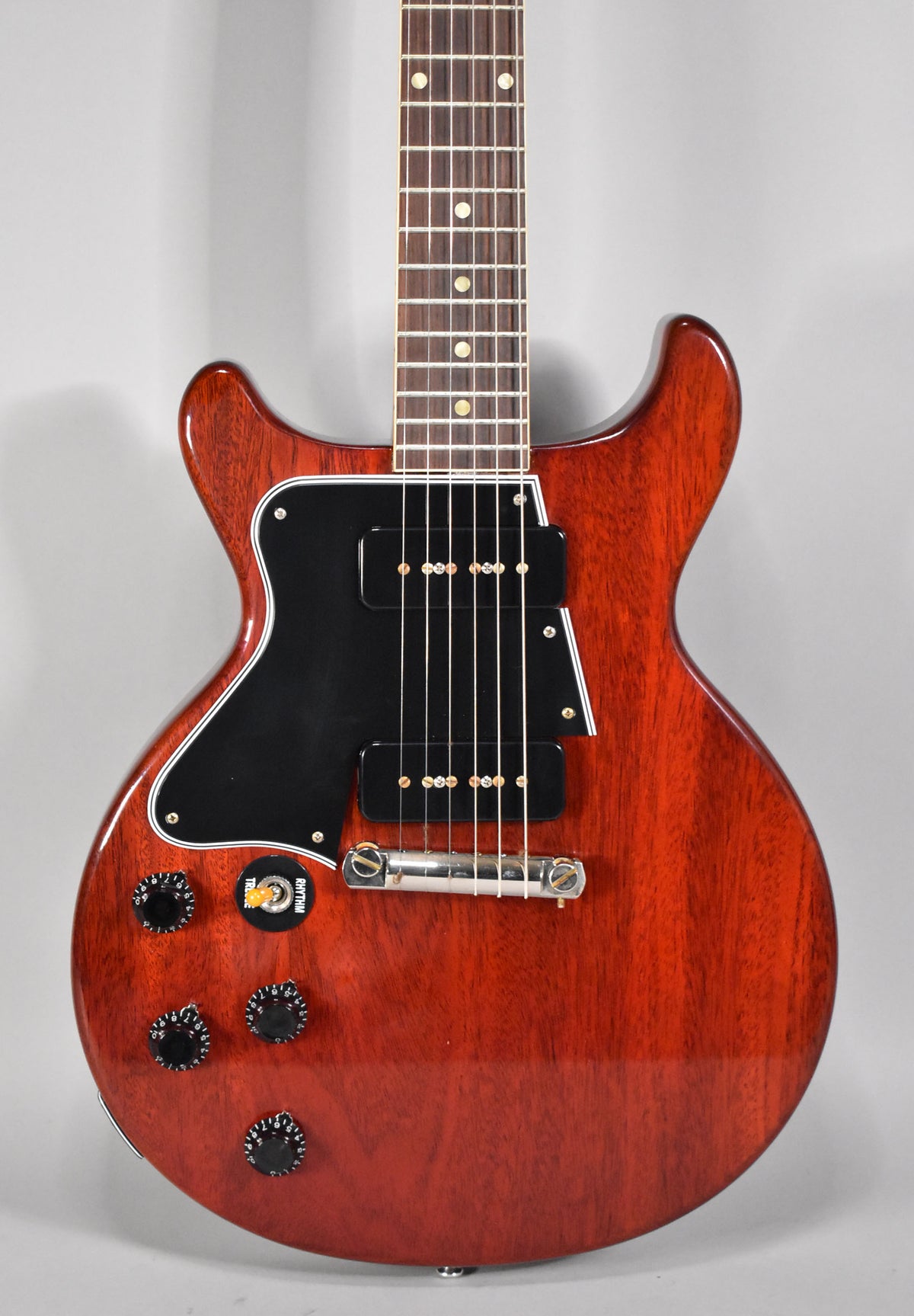 Faded cherry double-cut guitar, angled to show the body, black pickguard, two P90 pickups, and four black control knobs.