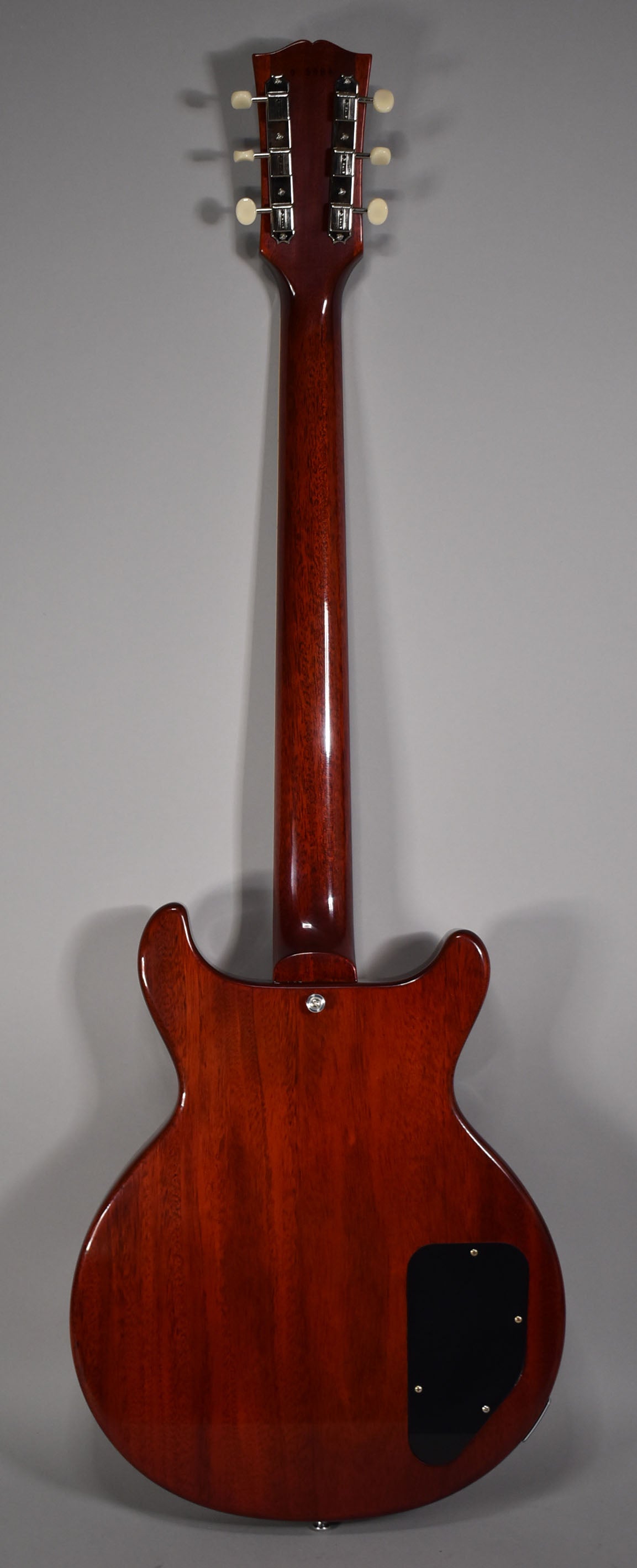Full rear view of the faded cherry double cut guitar, showing the headstock with cream tuners, neck, and body with a black control plate.