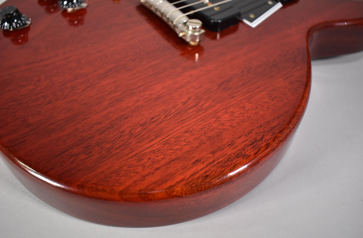 Close-up of the faded cherry body, showing wood grain, with black control knobs and part of the bridge visible at the top.