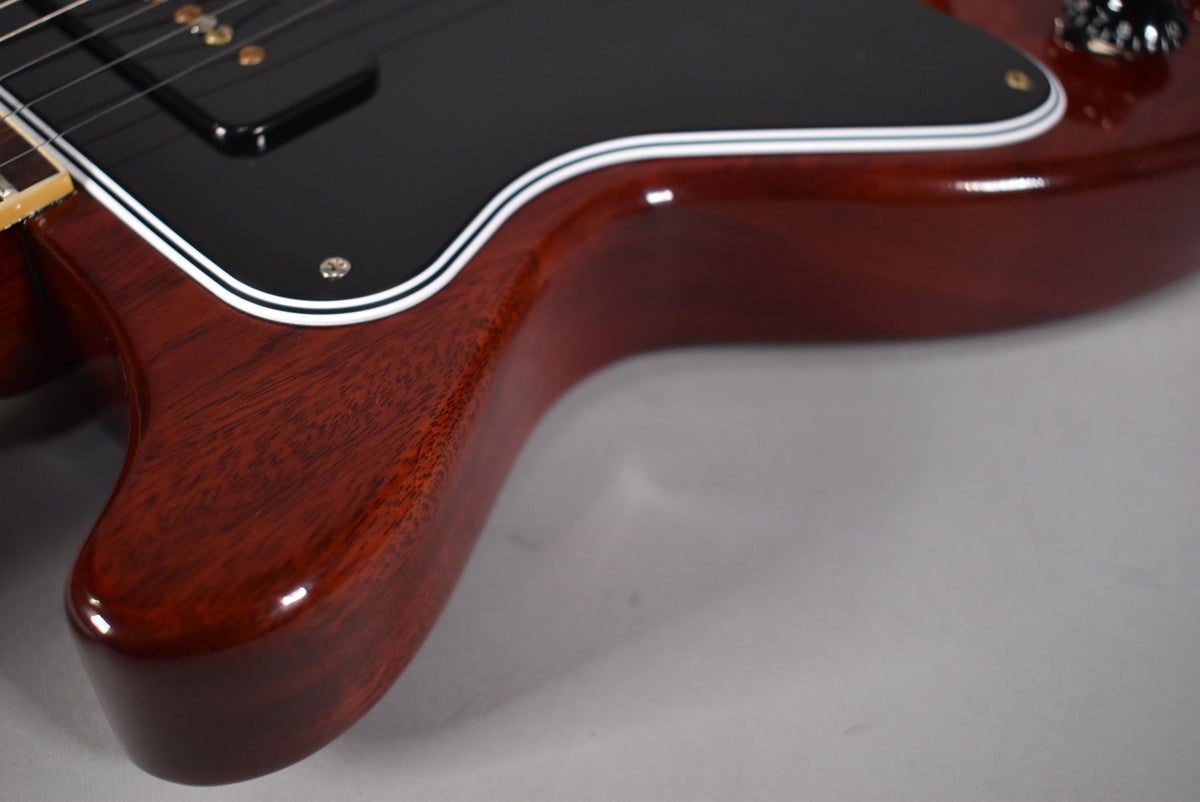 Close-up of the cherry-finished body, showing the lower cutaway and black pickguard with white binding, and a P90 pickup.