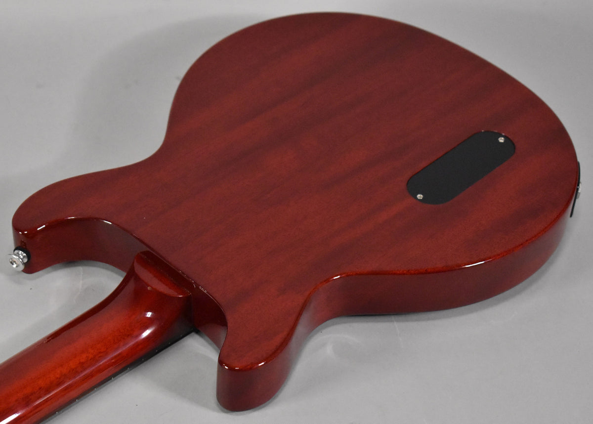 The back of the cherry red guitar body shows a black control cavity cover and a chrome output jack.