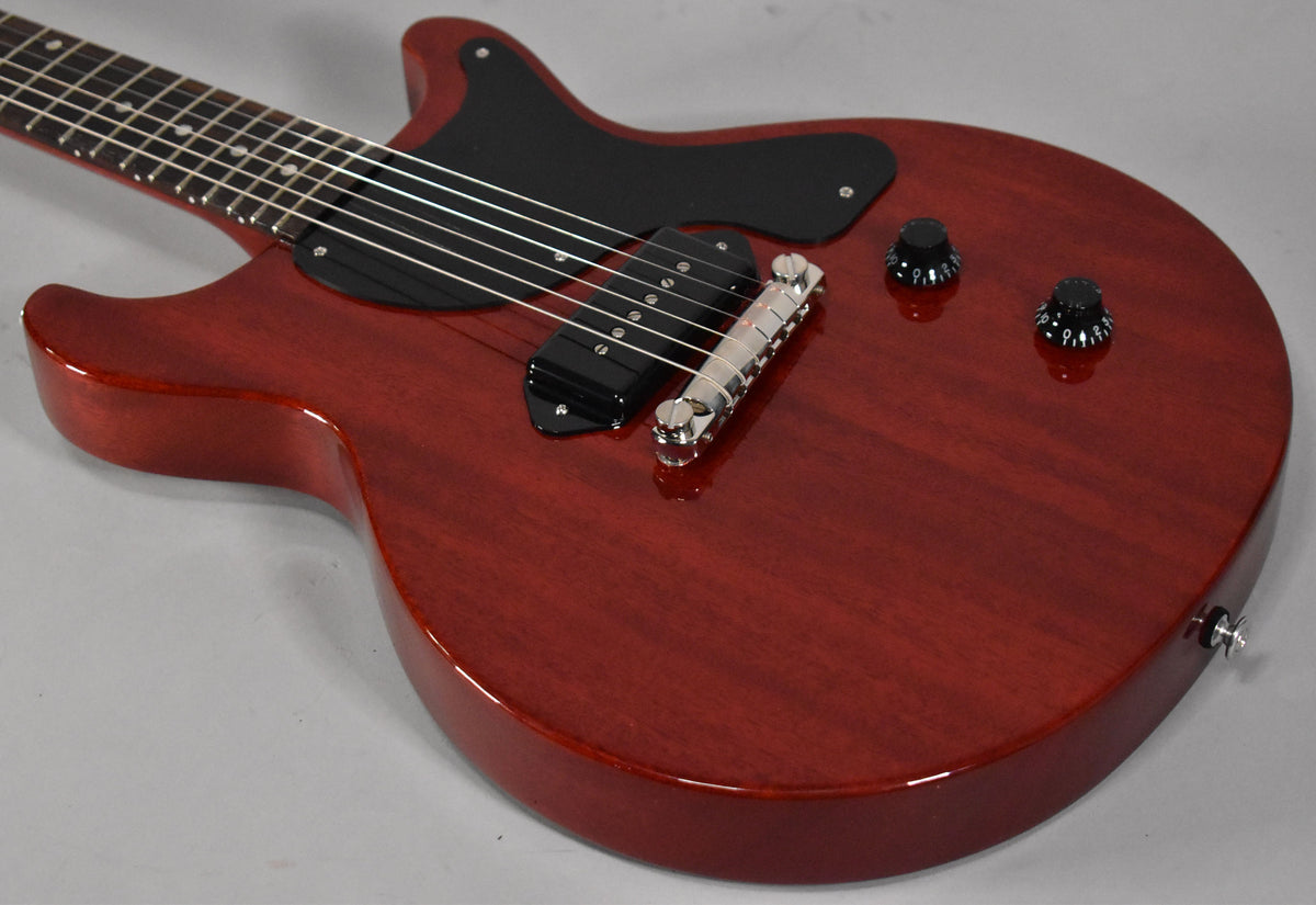 The guitar's body, finished in vintage cherry, is angled from the lower bout, showing a black pickguard, P90 pickup, and two black knobs.