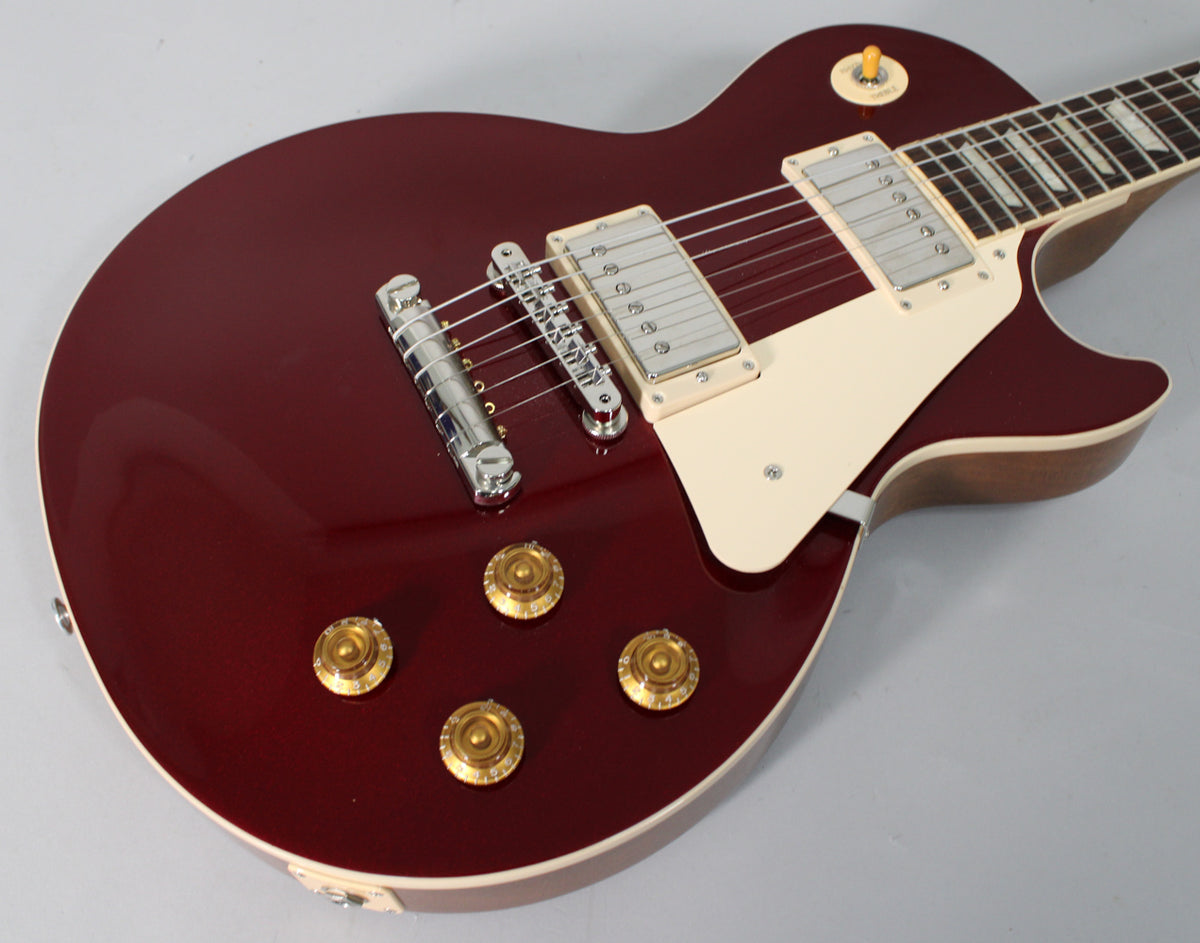 Sparkling burgundy Les Paul body, angled from the lower bout, showing cream binding, pickguard, gold top hat knobs, and chrome hardware.