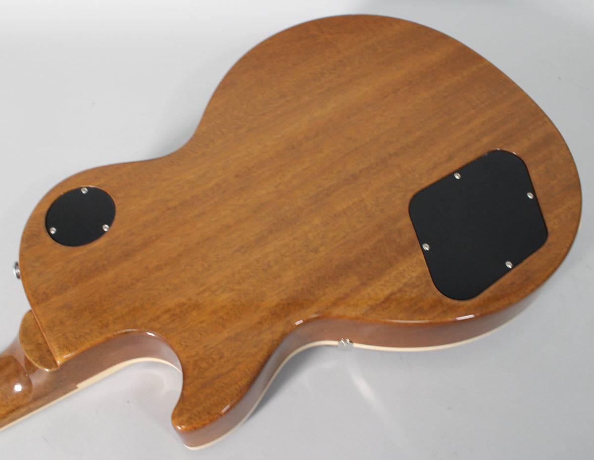 The back of a Les Paul, showing a glossy, reddish-brown wood grain finish with two black control cavity covers.