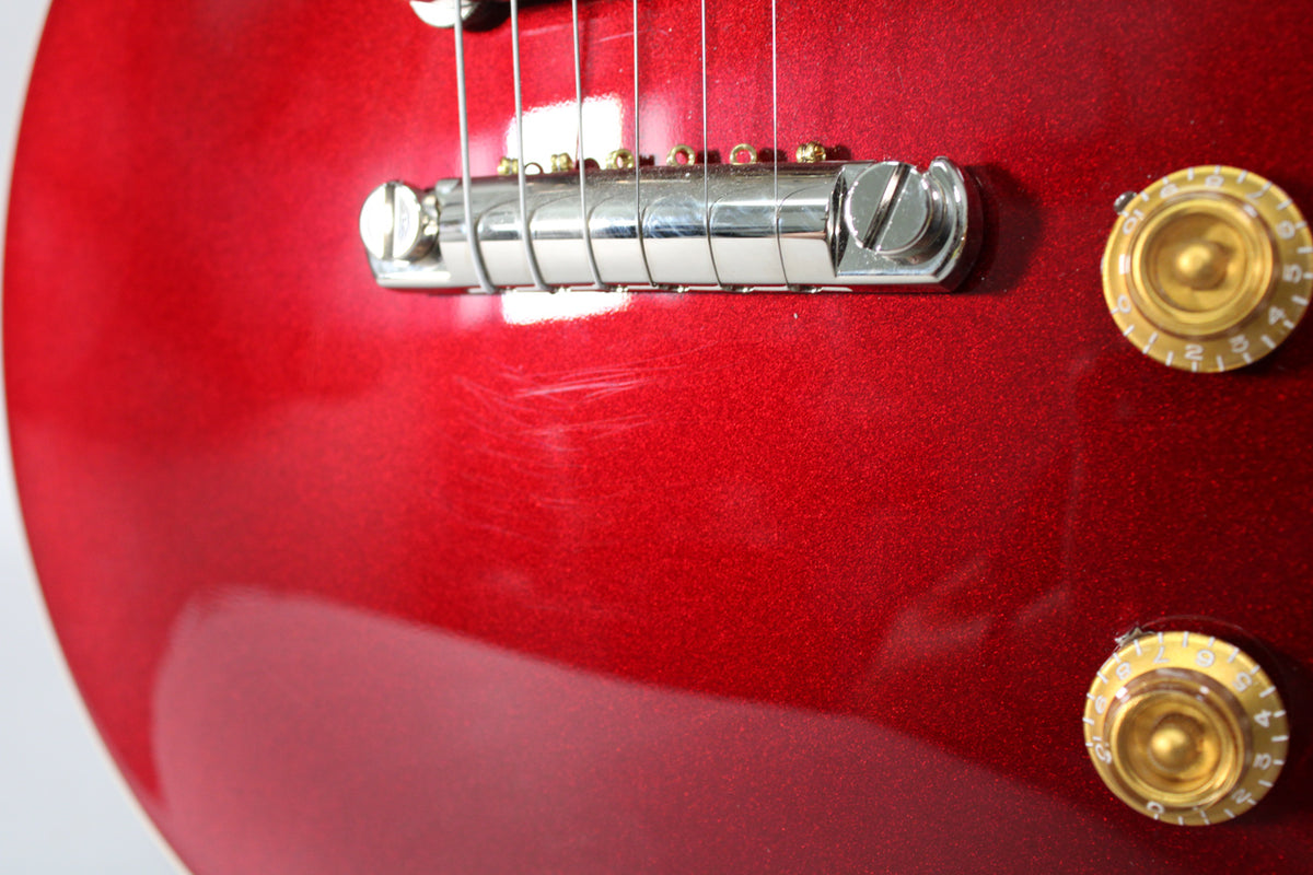 Close-up of the Sparkling Burgundy body, showing the chrome bridge, two gold top hat knobs, and light scratches below the bridge.