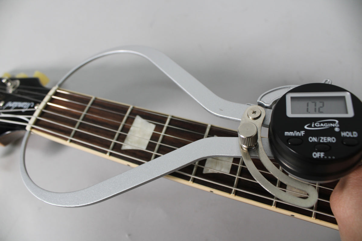 A digital caliper measures the nut width of the dark rosewood fretboard with trapezoid inlays, showing "1.72" on its screen.