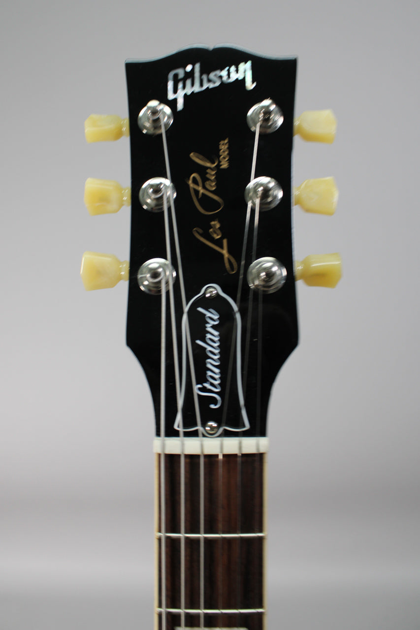 Close-up of the black headstock with cream tuners, chrome string posts, and a white truss rod cover.