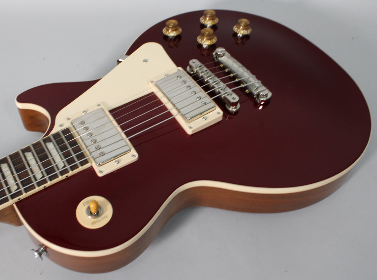 A sparkling burgundy Les Paul body with cream binding, two humbuckers, a cream pickguard, and four amber top hat knobs.