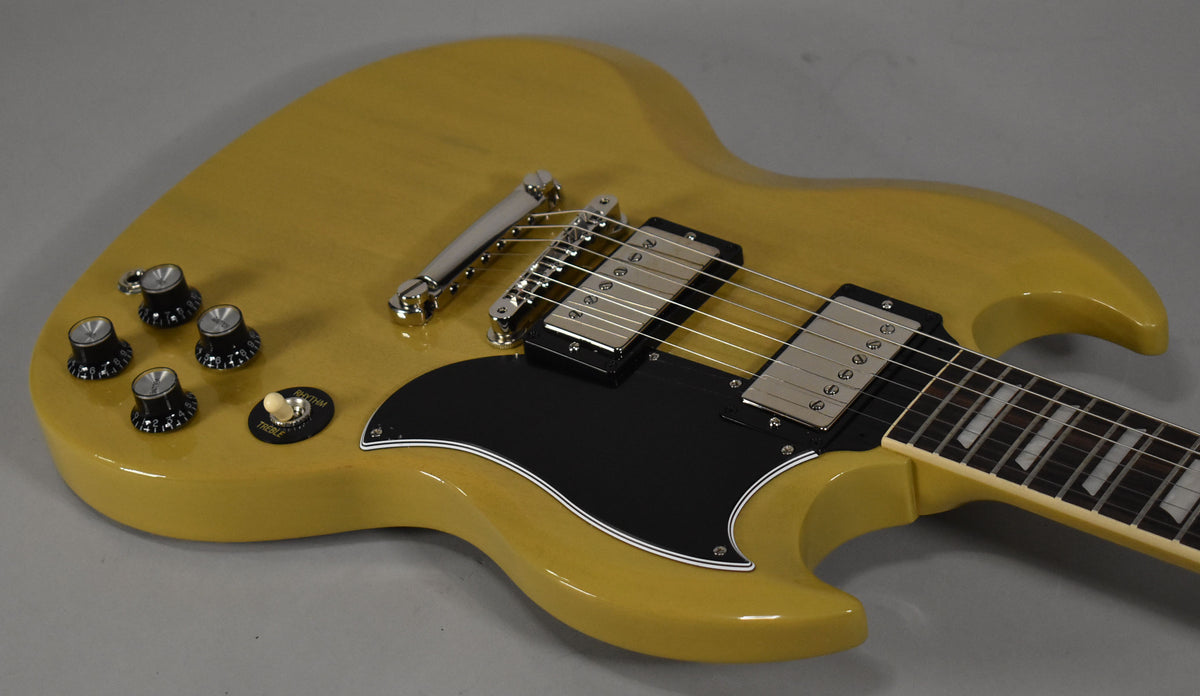 TV Yellow SG body, angled from above, showing the black pickguard, chrome hardware, four black knobs, and cream switch tip.