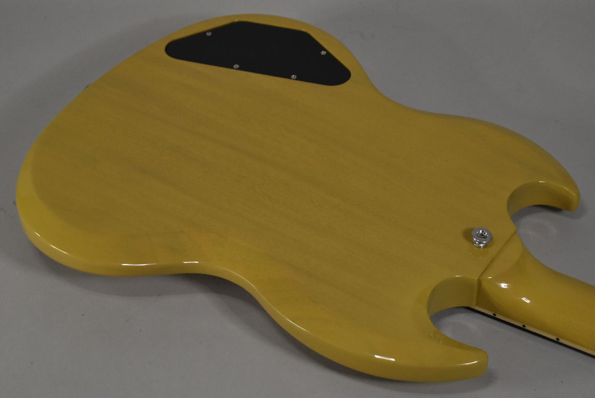 The back of a TV yellow SG guitar, angled from the lower bout, shows a black control cavity cover and a chrome strap button.