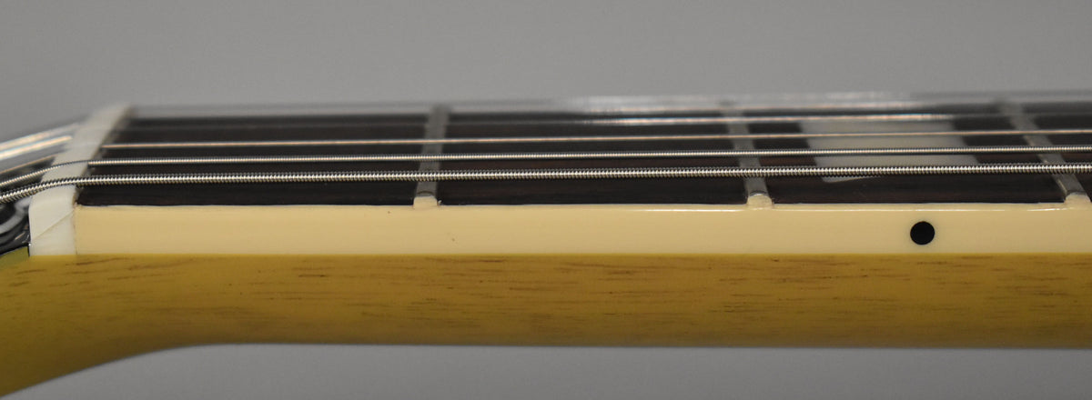 Close-up of the guitar's neck, showing the light-colored binding, dark fretboard, and a single black side dot marker.