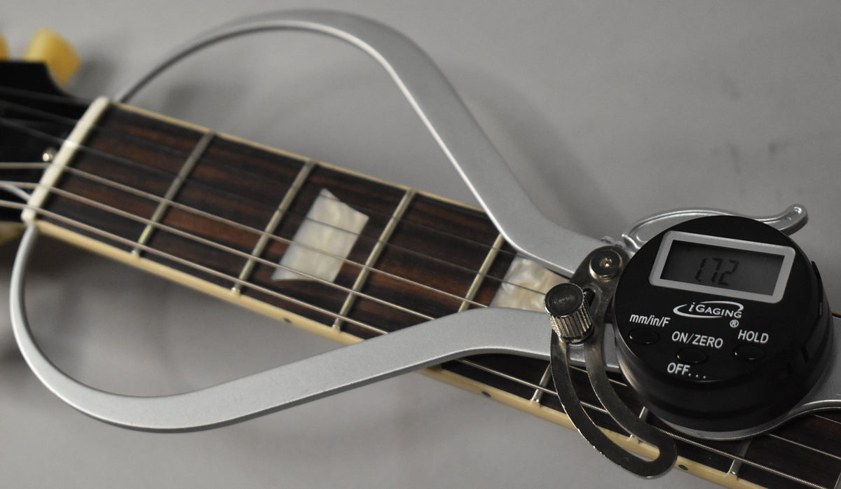 Close-up of the dark rosewood fretboard with trapezoid inlays, measured by a silver digital caliper displaying "1.72".