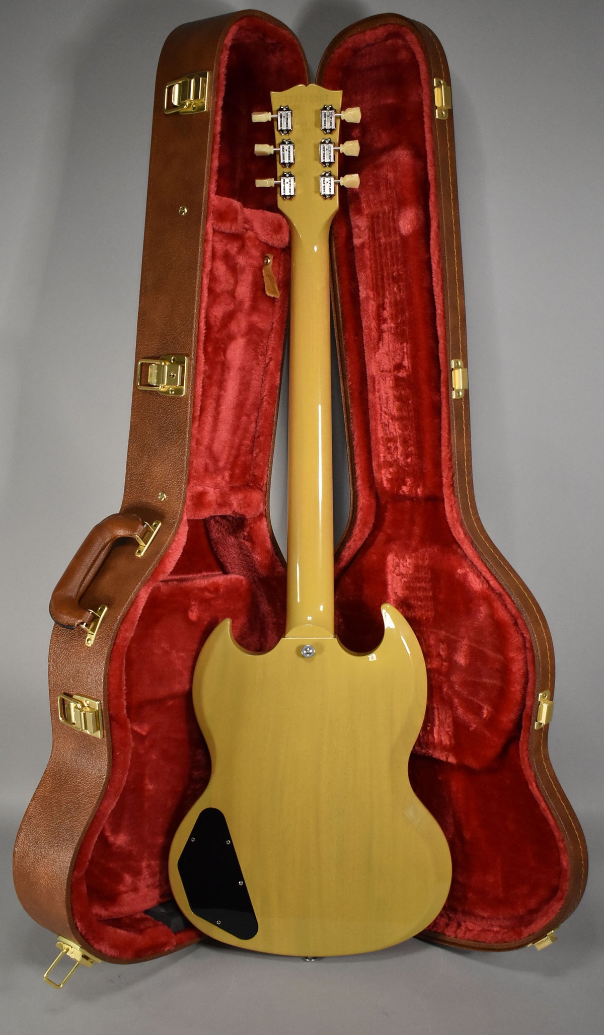 The TV Yellow SG is shown from the back, resting in its open brown hardshell case with red plush lining.