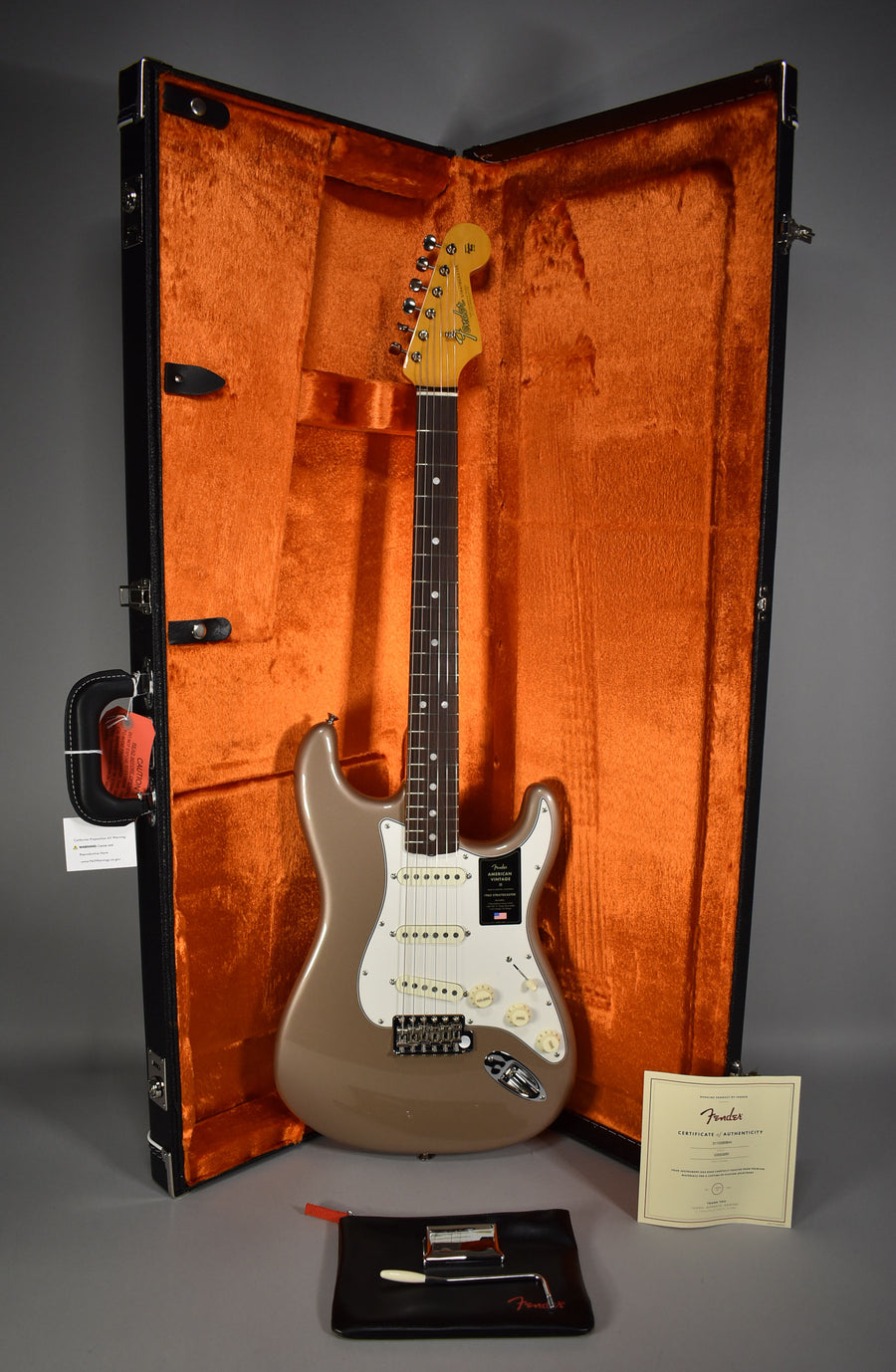 Full-length view of a Shoreline Gold Stratocaster with a white pickguard, chrome hardware, and a rosewood fretboard, in an open orange-lined case.