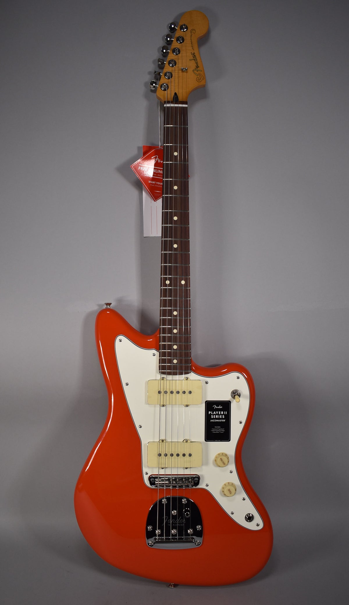 Full-body view of a glossy coral red Jazzmaster with a white pickguard, two cream P90 pickups, and chrome hardware.