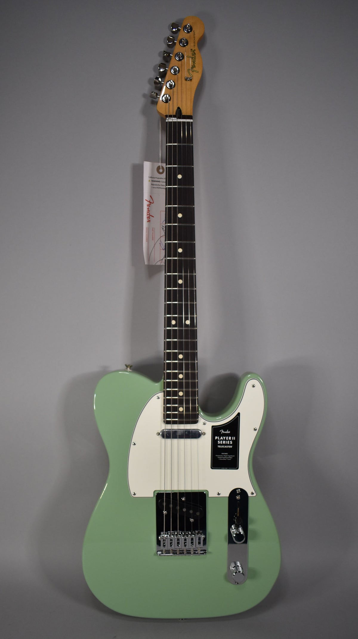Full-length view of a glossy birch green Telecaster with a white pickguard, chrome hardware, and a dark fretboard.