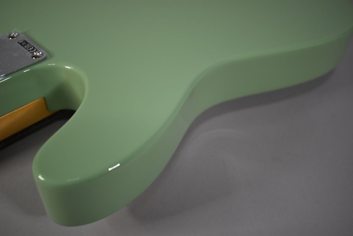 Close-up of the Telecaster's birch green body, showing the smooth, glossy finish and the neck joint with a chrome plate.
