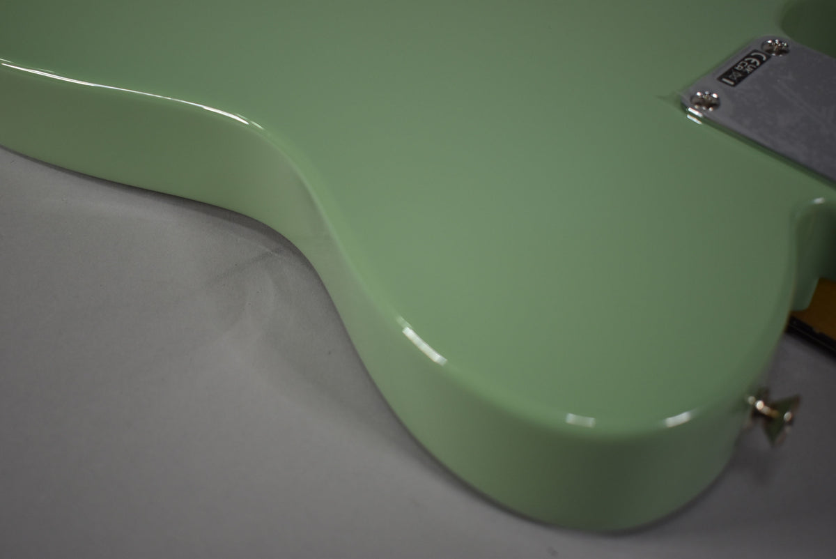Upper body of a glossy Birch Green Telecaster, angled from the lower left, showing the neck plate and strap button.